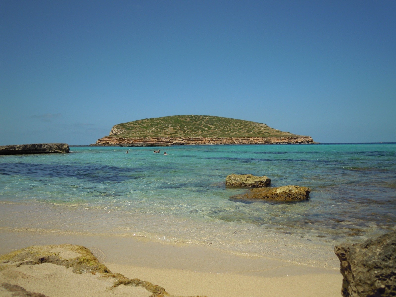 The clear shallow turquoise water and low rocky islets off Cala Comte on the west coast of Ibiza