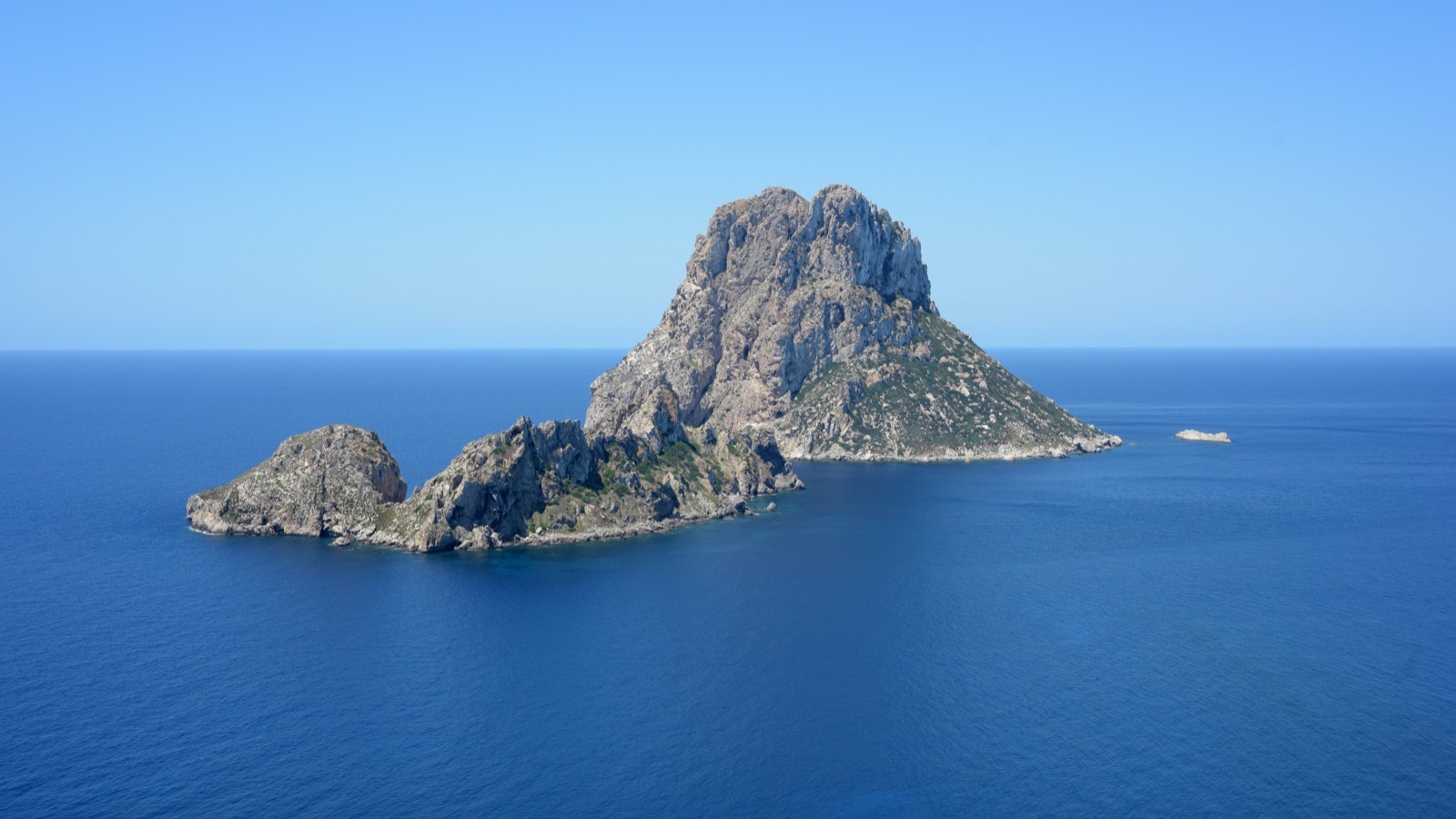 The rock islets of Es Vedra and Es Vedranell rising out of deep blue sea off the south west coast of Ibiza.
