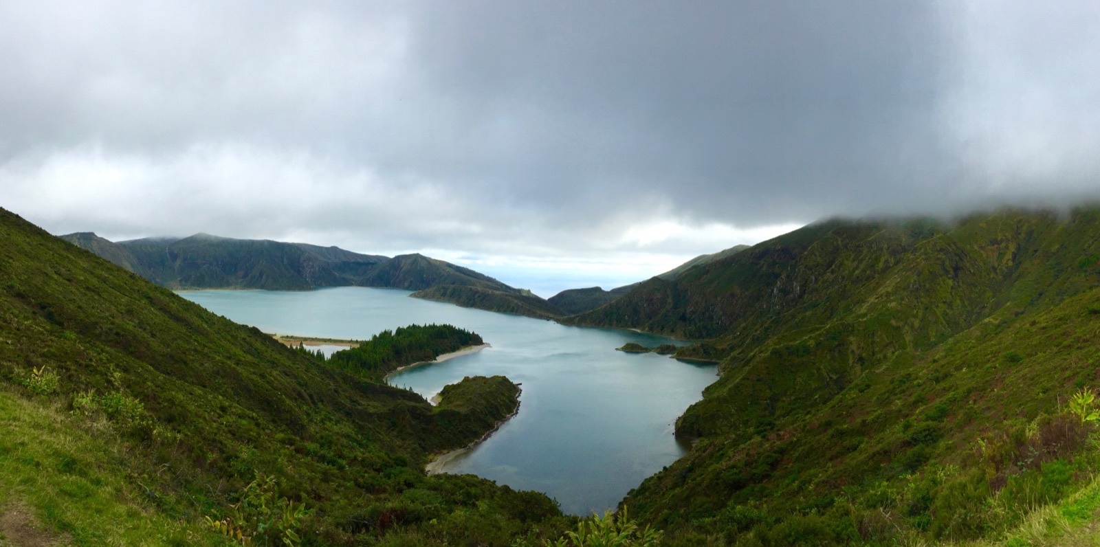 Lagoa do Fogo crater lake on Sao Miguel in the Azores, its pale shoreline curving below steep green slopes